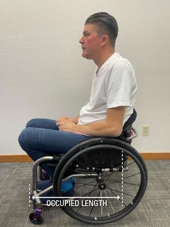 A diagram showing the occupied frame length of a man sitting in a wheelchair